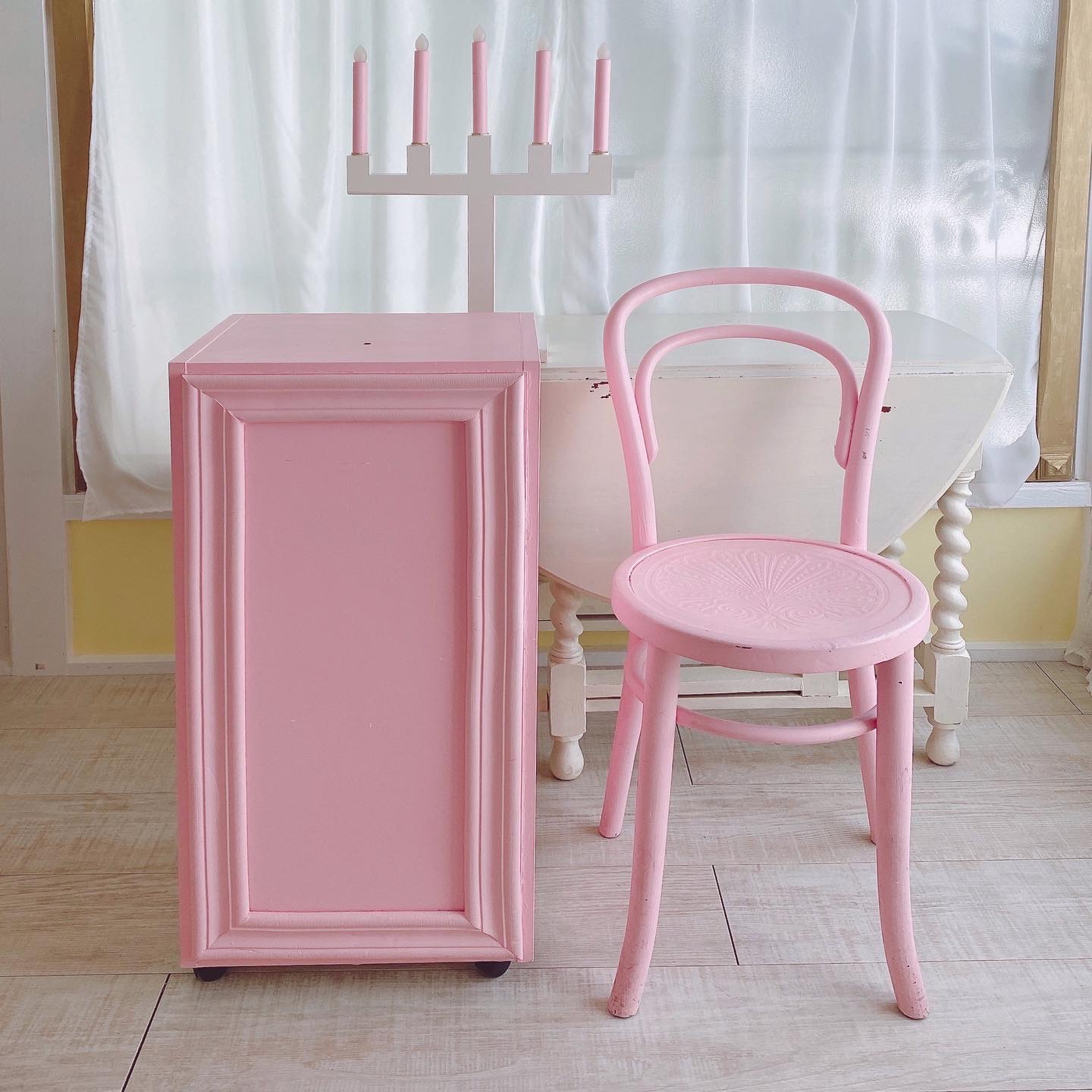 ピンクの棚、ピンクのチェア、キャンドル型のライト。
