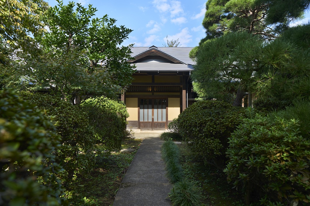 植栽越しに玄関を臨む情緒あるアプローチ。奥行きのある構図の撮影に最適です。