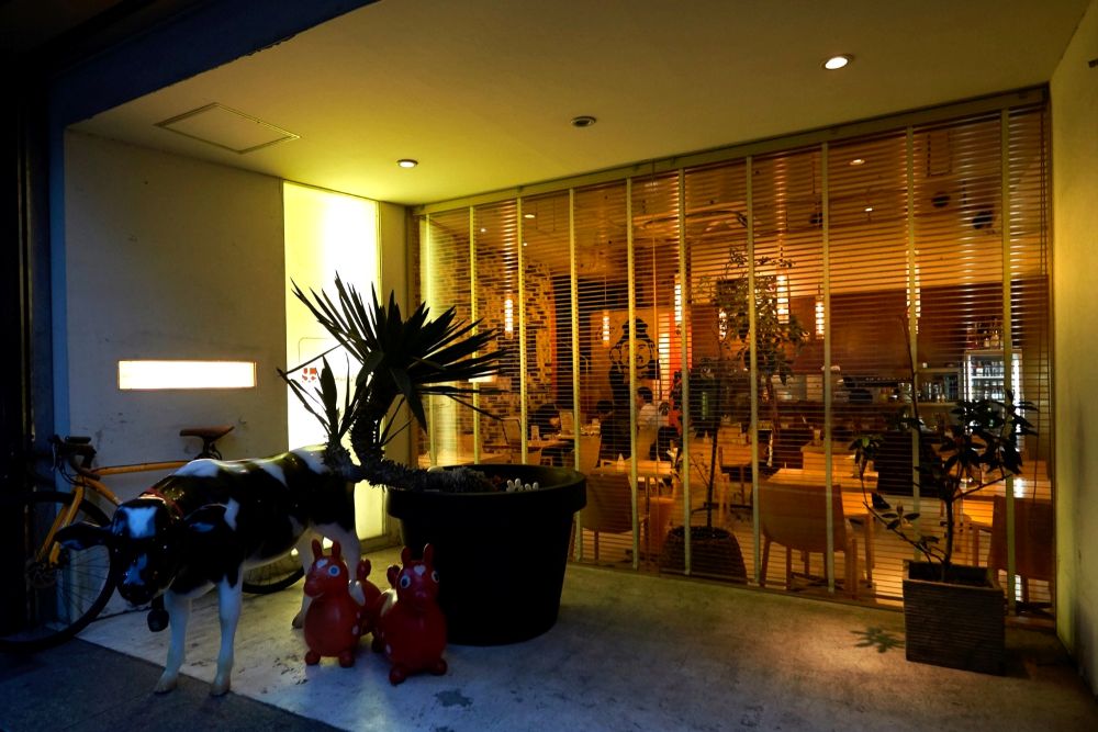 イエローカンパニー恵比寿本店の外観（夜）。ガラス越しに店内の温かい照明が見える開放的なファサードが特徴で、夜の導入カットや店舗外観シーンの撮影に適している。入口位置が分かりやすく、ロケハンや夜間撮影にも対応しやすい。